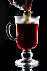 Process of preparing hot non-alcoholic mulled wine with orange and cinnamon on dark background