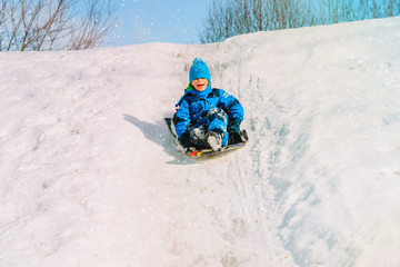 Fototapeta na wymiar kids winter fun- little boy sliding in snow