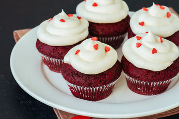 Red velvet cupcakes with cream cheese frosting on a white plate