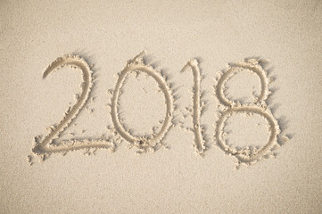 New Year 2018 message handwritten on a smooth sand beach in soft morning sunlight
