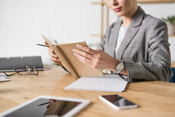 cropped shot of businesswoman with notebook sitting at workplace in office