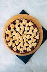 Cherry pie with heart shape decorations from flaky dough on a white backdrop