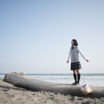 流木の上に立ち深呼吸をする女子校生