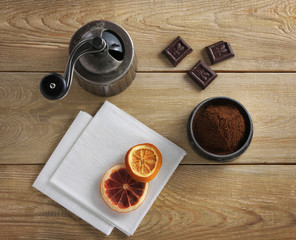 coffee grinder, chocolate & dried orange on a wooden table
