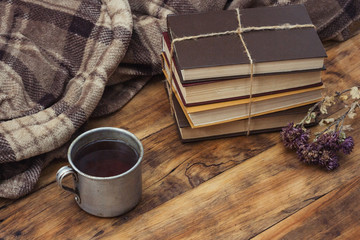 Amazing Image of a Metallic Cup with Hot Tea, Coffee, Warm Plaid, A Pile of Books Tied with a Rope on a Wooden Table