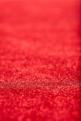 Portrait image at 45 degree angle of red glitter background iwith blur