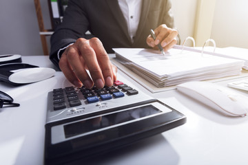 Close-up Of A Businessperson Calculating Bill