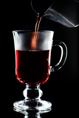 Process of preparing hot non-alcoholic mulled wine with orange and cinnamon on dark background