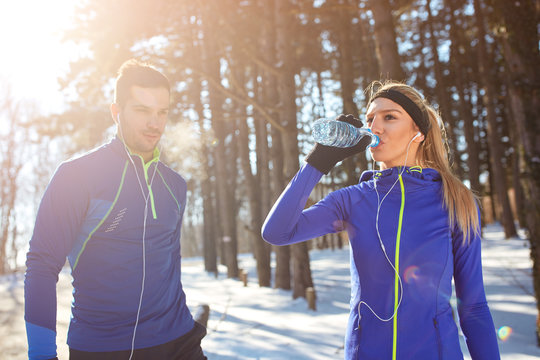 Woman drinking water in woods on training.