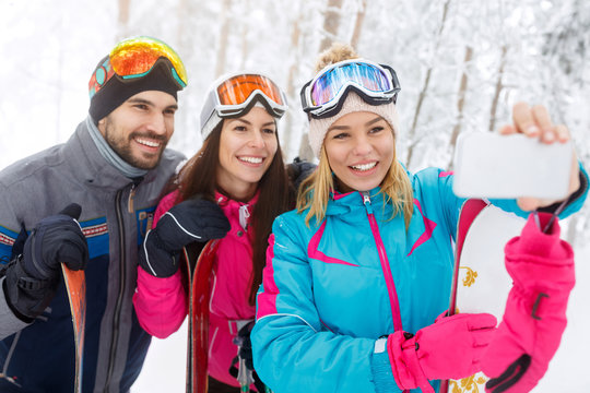 Woman with friends taking selfie on skiing
