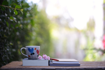 White mug with heart pattern and book with pink fairy rose