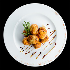 Delicious appetizing baked mushrooms with sauce in a white plate on dark background. Top view, flat lay