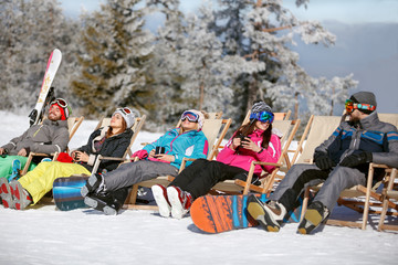 Skiers in sun bad sitting and pausing from skiing