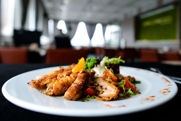 Delicious juicy roasted meat with spices and tomato in a white plate in a cafe, shallow dof