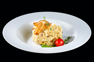 Traditional Italian cuisine. Appetizing creamy risotto with white mushrooms, basil and cherry tomatoes in a white plate