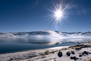 Beautiful panoramic view of Lake Cildir with snowy hills, reflection on the lake.