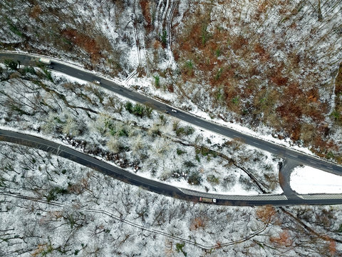 View from height on car driving through winter forest road. aerial eye landscape