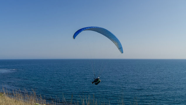A man flies on paraplane above the sea