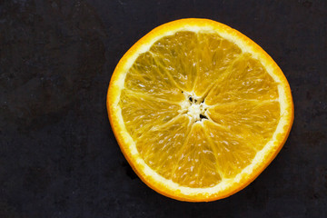 Slice of fresh orange on black background with copyspace