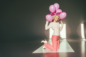 blonde stylish woman posing with pink balloons