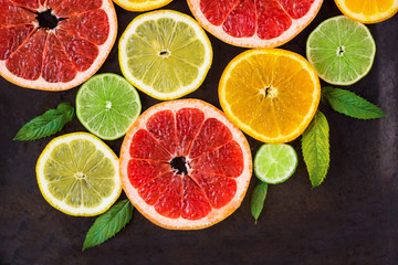 Fototapeta na wymiar corner with slice of oranges, lemons, limes, grapefruit and mint pattern on black. Flat lay