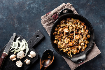 Mushrooms champignon fried with onion in pan, top view