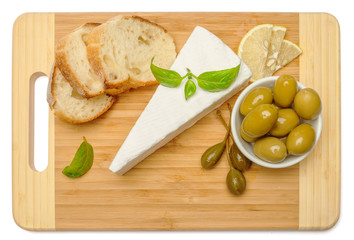 brie or camambert cheese and olives on a white background