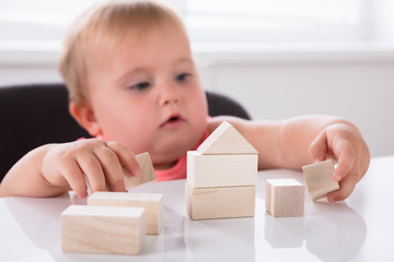 Baby Girl Making House From Wooden Blocks