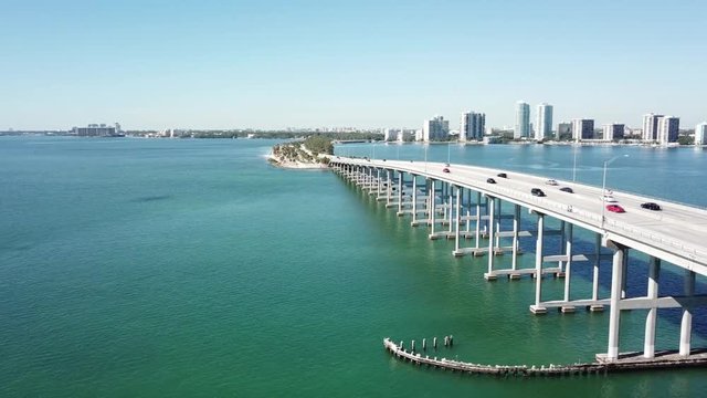 Majestic 4k aerial drone panorama shot of highway road on huge steel modern bridge across turquoise blue ocean cityscape