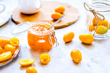 kumquat on plate and jam in jar at gray background