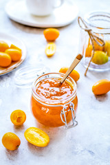 kumquat on plate and jam in jar at gray background