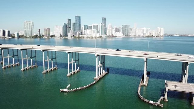 Glorious 4k aerial drone panorama shot of highway road on huge steel modern bridge across turquoise blue ocean cityscape