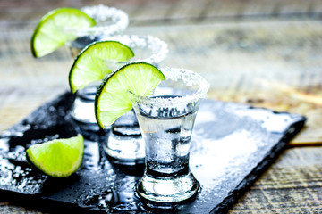 Party in bar with tequila, salt and lime on wooden table