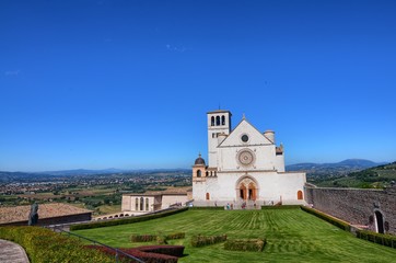 Front view of the Basilica of Saint Francis of Assisi. Sunshine spikes from behind the basilica,...