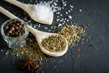  Wooden spoon with Italian seasoning - dried oregano with thyme, basil and vegetables .Oregano in a wooden spoon on a rocky concrete dark black background with a place for text Top view. A wooden spoo