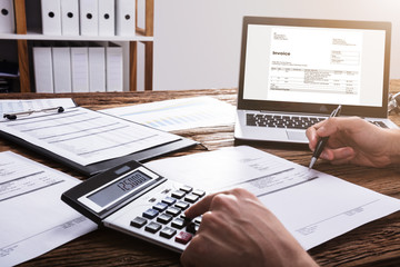 Businessperson's Hand Calculating Bill With Calculator