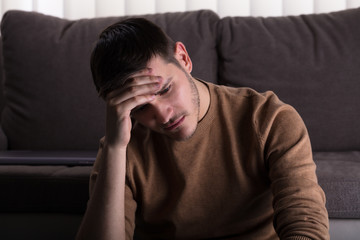 Sad Man Sitting In Front Of Sofa