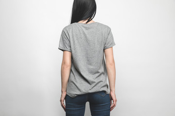 rear view of young woman in blank grey t-shirt on white