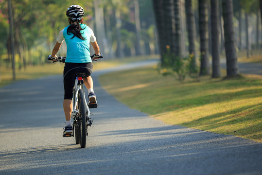 female cyclist riding bike in tropical park