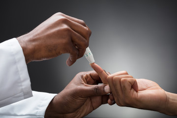 Doctors Hands Using Lancet To Check Blood Sugar Level