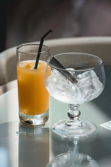 Fresh alcoholic cocktail. Vodka, melon liquor orange juice ice. Cocktail on a glass table