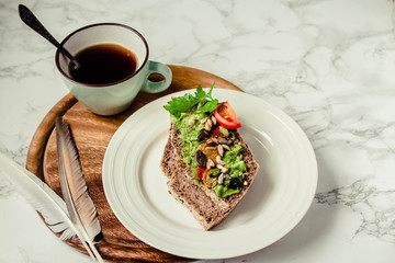 Toast of gluten fries with guacamole with tomatoes, seeds and herbs. A cup of coffee. Breakfast. Wooden board.Marble background. Top view.