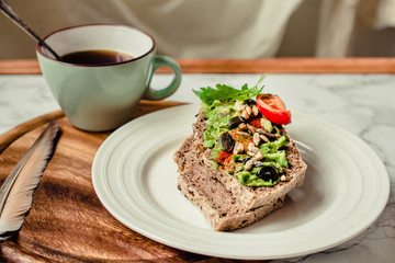 Toast of gluten fries with guacamole with tomatoes, seeds and herbs. A cup of coffee. Breakfast. Wooden board. Selective focus.