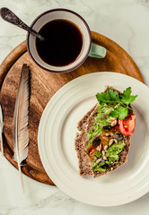 Toast of gluten fries with guacamole with tomatoes, seeds and herbs. A cup of coffee. Breakfast. Wooden board.