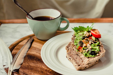 Toast of gluten fries with guacamole with tomatoes, seeds and herbs. A cup of coffee. Breakfast. Wooden board. Selective focus.