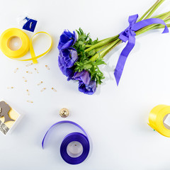 Concept of preparation for the holiday or wedding. Blue flowers, card, ring, yellow and blue ribbon on light background. Top view, flat lay