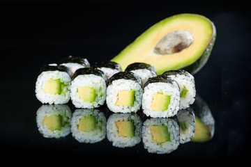 Fresh delicious Japanese sushi with avocado on dark background