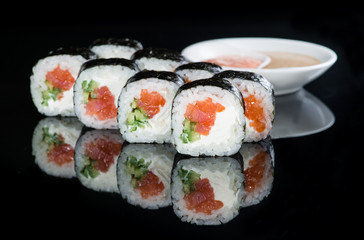 Japanese cuisine. Appetizing maki sushi rolls with rice, salmon, salmon and cucumber on dark background