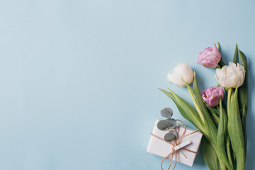 Mother's Day Composition: Violet and white tulips and a gift boxes on a blue background. Top view.Flat lay.