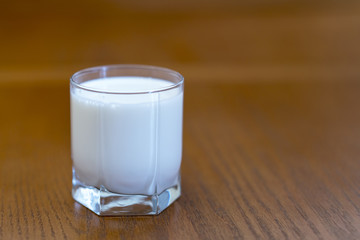 A glass of milk on a brown background.